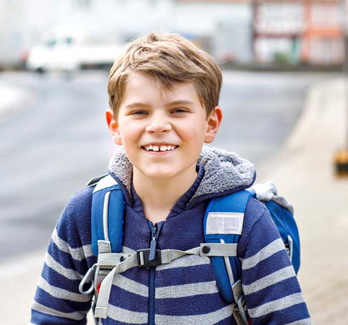 boy with blue jacket and backpack outside