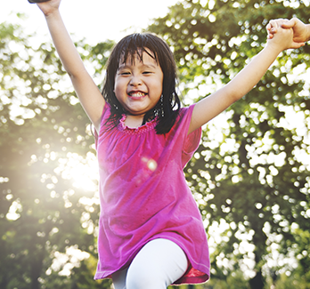 girl in pink shirt with arms up